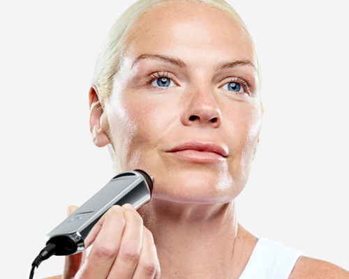 Mature woman demonstrating use of CurrentBody RF radio frequency device for facial skin firming